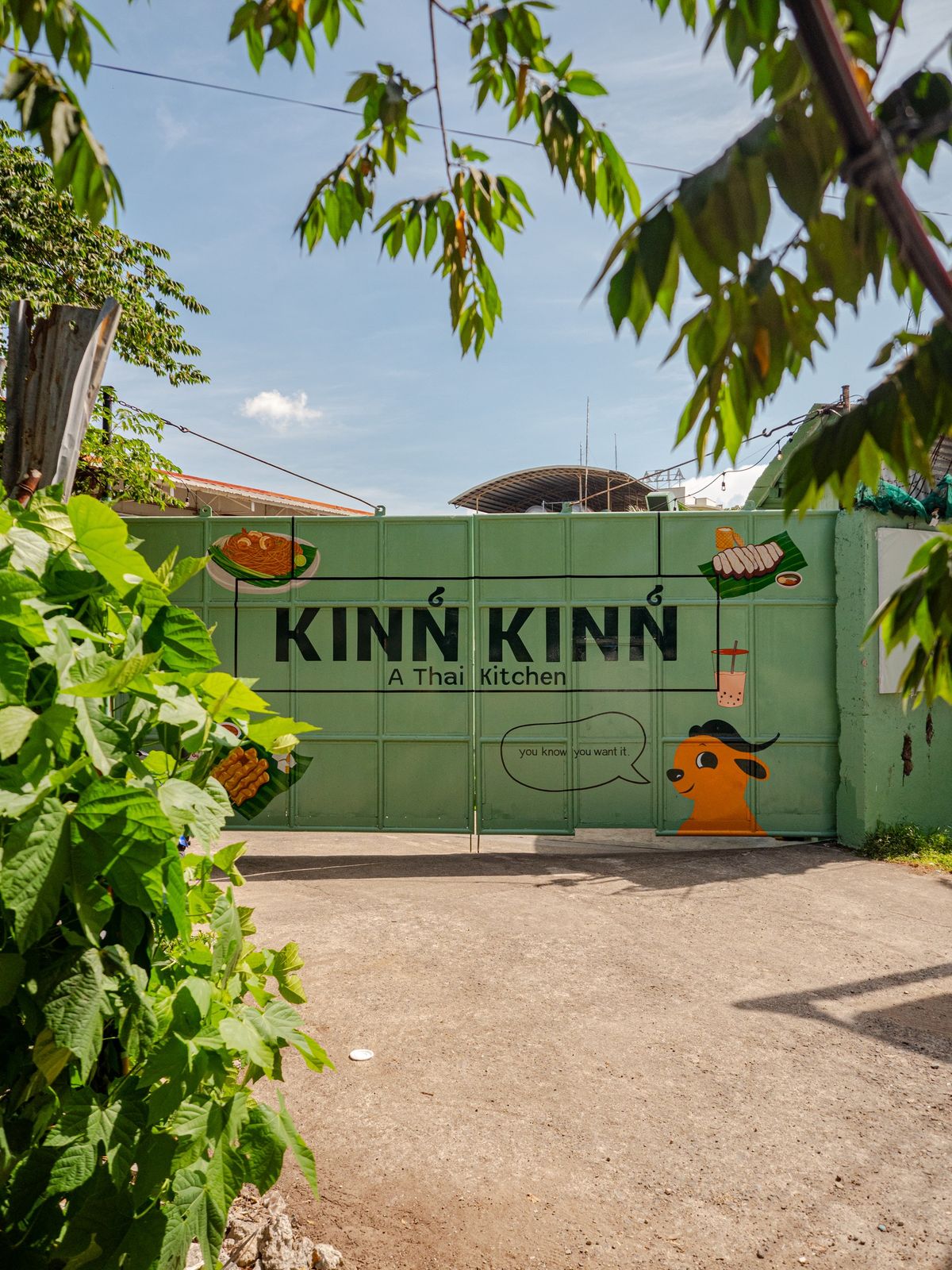 The green gate on F. Sotto Drive, painted with the Kinn Kinn wordmark and Buffy the mascot